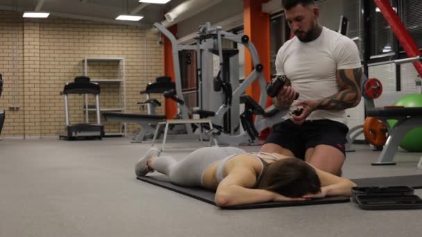 Προσωπικός γυμναστής που χρησιμοποιεί όπλο μασάζ στο σώμα της αθλήτριας - Πλάνα, βίντεο