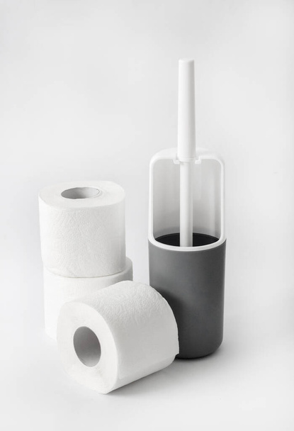 Cepillo higiénico de plástico blanco y gris y rollo de papel higiénico sobre fondo blanco - Foto, Imagen