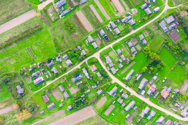 Beau petit village verdoyant d'en haut, chemins de terre, rues, potagers, champs labourés, prairies, maisons. Vue aérienne du dessus - Photo, image