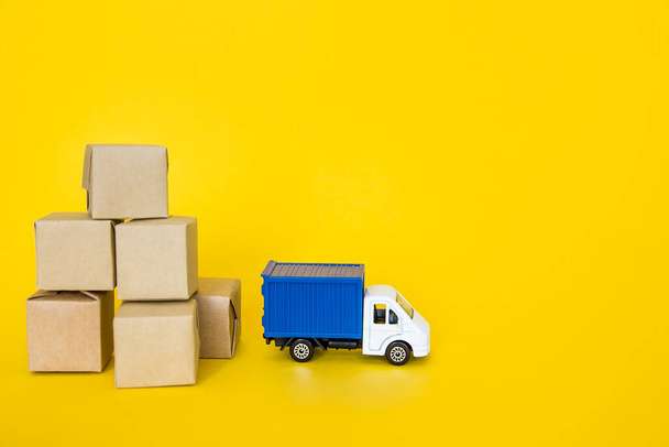 Κουτιά χαρτοκιβωτίων και ταχυδρομικό φορτηγό σε κίτρινο φόντο. Μεταφορά φορτίου, υπηρεσία παράδοσης. - Φωτογραφία, εικόνα