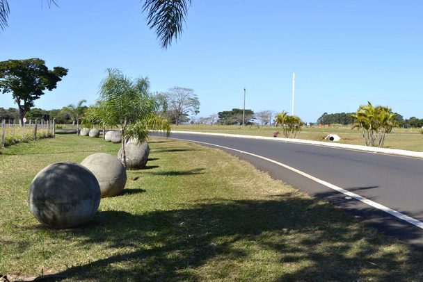 Estrada. Estrada de asfalto no interior do Brasil, América do Sul, com artefatos de cimento em exposição ao lado da estrada rolante com uma torre ao fundo - Foto, Imagem