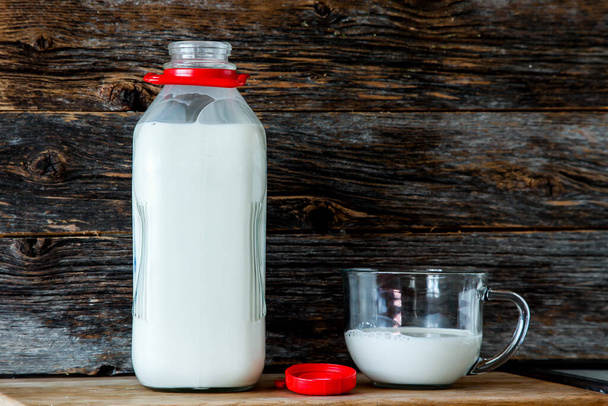 Mutfakta kırsal görünümlü ahşap arka planlı organik süt şişesi. - Fotoğraf, Görsel