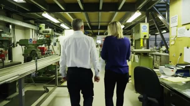 Liikekumppanit kävelevät yhdessä valvomaan tehtaan toimintaa
 - Materiaali, video