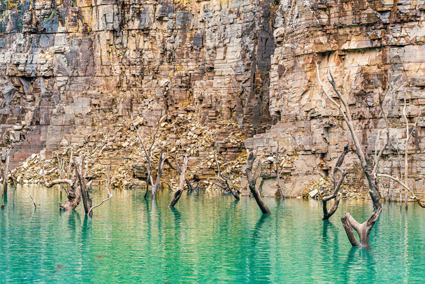 Alberi sommersi con rami secchi che fuoriescono dall'acqua del lago, circondati da pareti rocciose di rocce sedimentarie. Bellissimo paesaggio del lago di Furnas, Capitolio MG, Brasile. - Foto, immagini