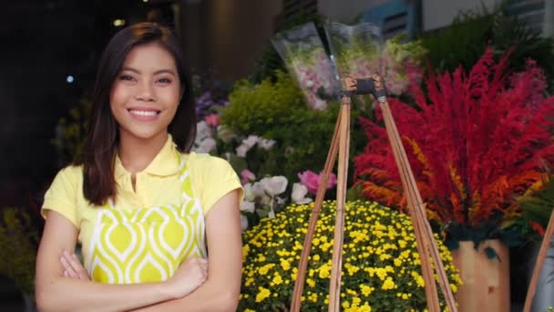 Mediana toma de la joven mujer asiática en delantal de pie en la tienda de flores, mirando a la cámara y sonriendo - Metraje, vídeo