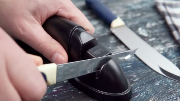 Mann wetzt Messer auf einem Schleifstein in der Küche - Filmmaterial, Video