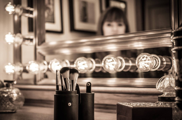 accesorios de maquillaje vanidad vintage, tocador de maquillaje con mujer indefinida en el espejo - Foto, Imagen