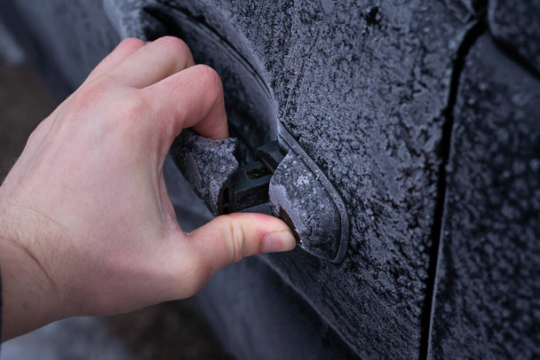 Tratando de abrir la puerta de un coche congelado en la mañana en invierno - Foto, imagen