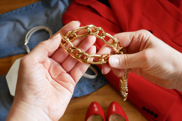 manos con gran cadena dorada en la ropa con chaqueta, bolso, jeans, zapatos para el fondo del traje de la mujer moderna, primer plano - Foto, Imagen