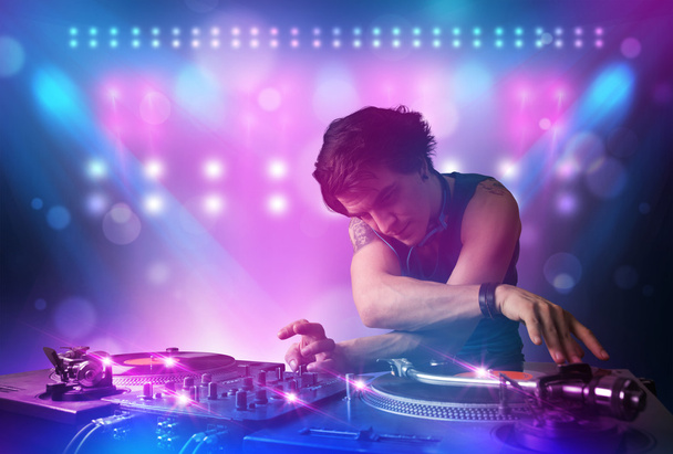Disco jockey mezcla de música en los tocadiscos en el escenario con luces y
  - Foto, imagen