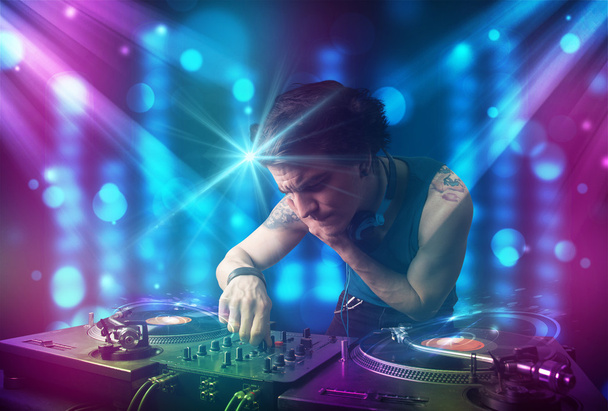 DJ mixen van muziek in een club met blauw en paars lichten - Foto, afbeelding