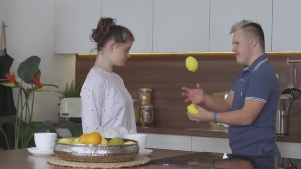 Young couple with Down Syndrome juggle at kitchen - Footage, Video