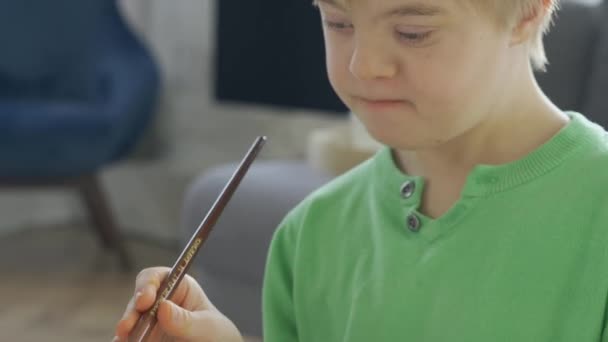 Primer plano del niño con síndrome de Down dibujo en casa - Imágenes, Vídeo