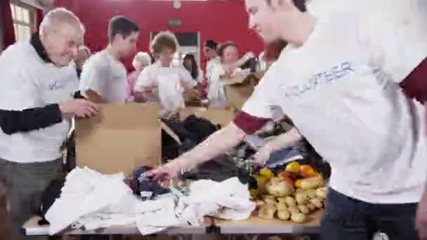 grote groep van liefdadigheid vrijwilligers sorteren door middel van gedoneerde goederen - Video