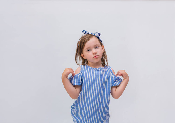 Overstuur klein meisje in een gestreepte blouse op een witte geïsoleerde achtergrond met ruimte voor tekst - Foto, afbeelding
