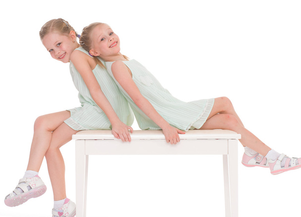 Cute sisters having fun sitting on a chair. - Photo, image