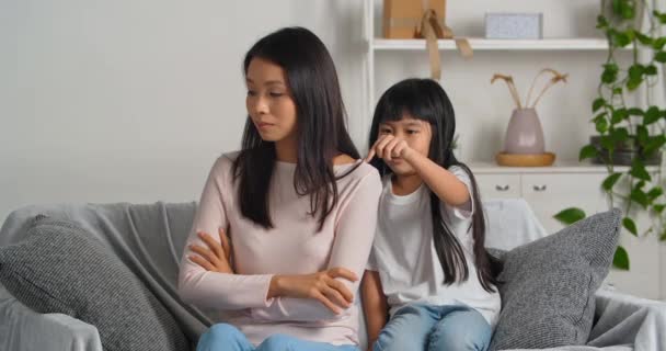 Mujer asiática madre ofendida siente tristeza y estrés de niño malentendido está preocupado por la diferencia generacional pequeña hija acariciando su mamá consuela alivia se disculpa por mal comportamiento - Imágenes, Vídeo