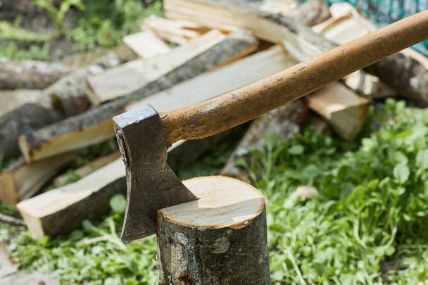 Beil oder Beil für das Häckseln von Holzstämmen steht bereit, um Holz zu schlagen. Nahaufnahme der Axt vor Baumstämmen, die im Hintergrund liegen - Foto, Bild