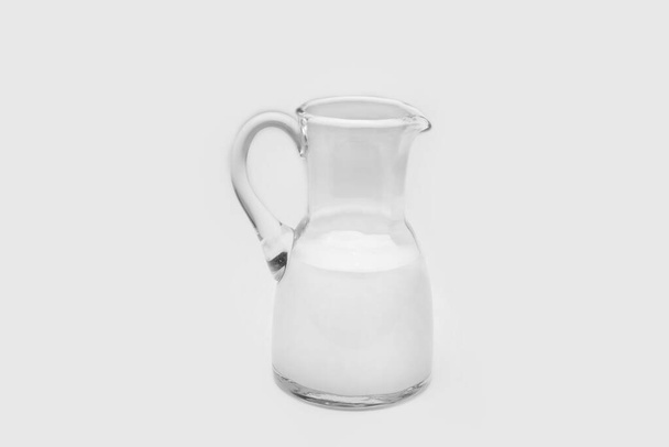 Glass pitcher half full with milk on a white background - Photo, Image