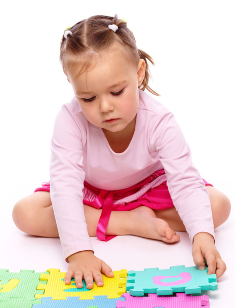 cute dziewczynka bawi się z alfabetu, siedząc na podłodze, na białym tle nad białym - Zdjęcie, obraz