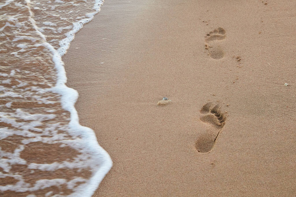 Відбитки ніг на березі моря біля моря
 - Фото, зображення