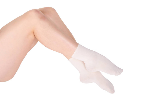 Female legs in white cotton socks on white background. Ladies wearing sports socks - Photo, image