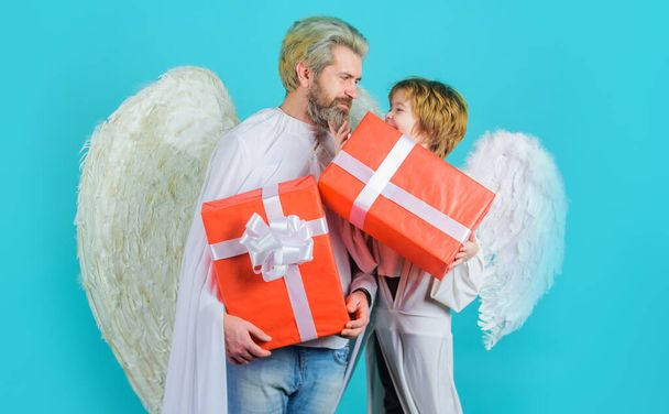Happy father with son in angel costume with present. Valentines angels with gift box. Little cupid boy gives father gift. - Photo, Image