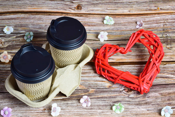 Puinen tausta, kaksi kuppia kahvia oikealla ja suuri koriste paju sydän oikealla. Pienet kukat ovat hajallaan ympäri - Valokuva, kuva