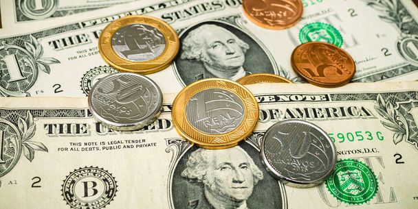 Brazilian coins and a US One Dollar bills on a wooden table. Top View photo. Foreign exchange market concept. - Foto, imagen
