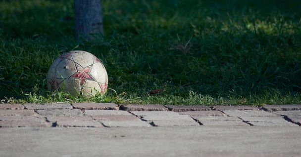 Pelota de futbol gastada aislada sobre el cesped - Foto, Bild