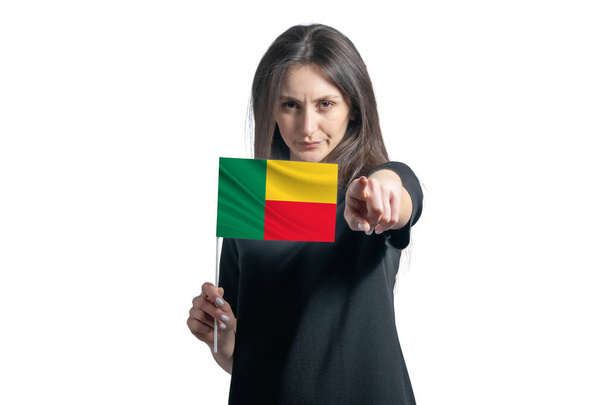 Heureuse jeune femme blanche tenant le drapeau du Bénin et pointant vers l'avant devant lui isolée sur fond blanc. - Photo, image