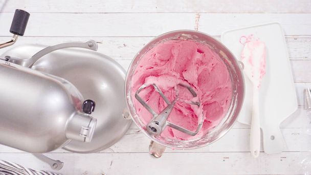 Acostado. Preparación de crema de frambuesa crema de queso en mezclador de cocina para hornear cupcakes de chocolate con frambuesa. - Foto, Imagen