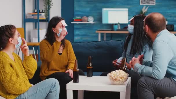 Různorodá skupina zábavných lidí v obývacím pokoji hrát s lepkavé papíry - Záběry, video