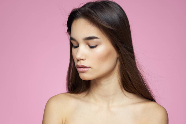 brunette bare shoulders clear skin body care pink background - Фото, изображение