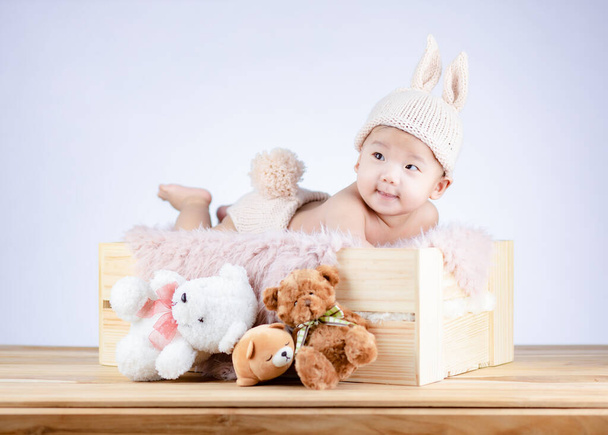 かわいい赤ちゃんウサギの衣装上の木の箱. - 写真・画像