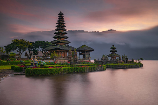 Pura Ulun Danu Bratan temppeli Balin saarella. Kaunis balilainen temppeli auringonnousun aikana. Balilainen maamerkki. Pilvinen taivas. Vedenheijastus. Hidas suljinnopeus. Bratan järvi, Bali, Indonesia - Valokuva, kuva