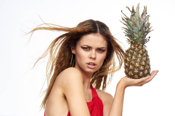 Woman with pineapple in hands wavy hair red t-shirt fruits summer vacation light background - Foto, Imagem