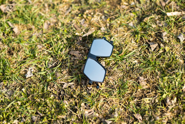 Modelo de gafas de sol futuristas de gran tamaño con lentes de color plateado que disparan al aire libre sobre hierba en un primer plano de día soleado. Enfoque selectivo - Foto, imagen