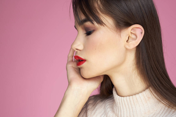 Jolie brune dans un pull blanc lèvres rouges look attrayant fond rose - Photo, image