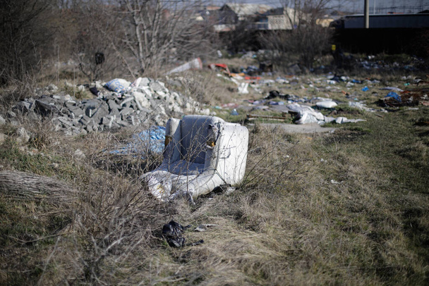 Shallow depth of field details of garbage and construction debris scattered all around an empty lot in Bucharest, near a makeshift shelter. - Photo, Image