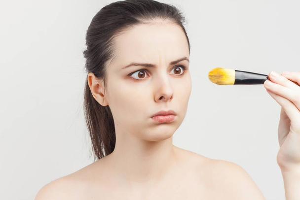 bare-shouldered brunette applying makeup on face cropped view - Valokuva, kuva