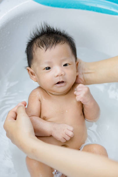 Recém-nascido tendo um banho na bacia pela mãe - Foto, Imagem