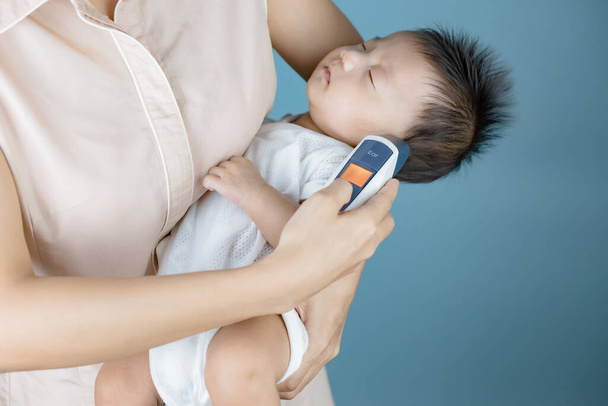 Mutter misst Temperatur des Babys mit elektronischem Thermometer - Foto, Bild