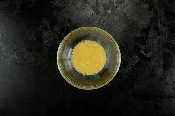 Beaten whole eggs  in a glass bowl on background, close up - Fotografie, Obrázek