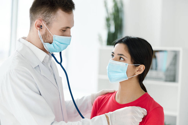médecin examine femme en masque médical rouge t-shirt stéthoscope santé - Photo, image