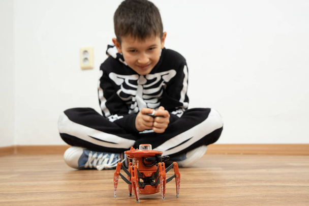 Niño jugando con araña robot juguete en el suelo en casa - Foto, imagen