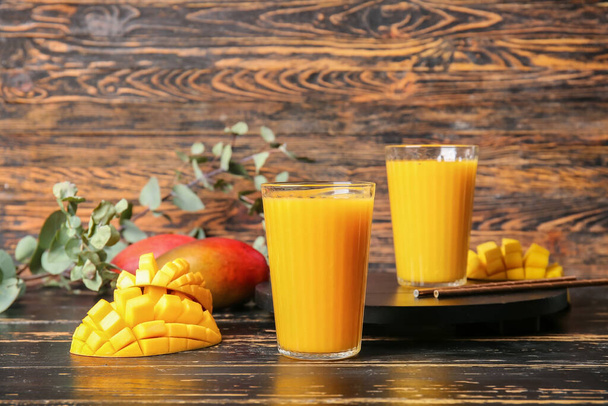 Gläser leckerer Mango-Smoothie auf dunklem Holzhintergrund - Foto, Bild