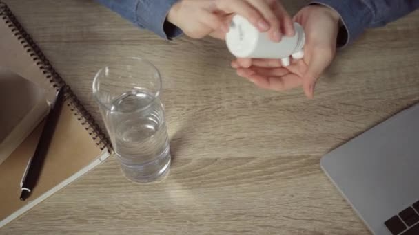 częściowy widok kobiety trzymającej butelkę i tabletki w pobliżu szklanki wody - Materiał filmowy, wideo