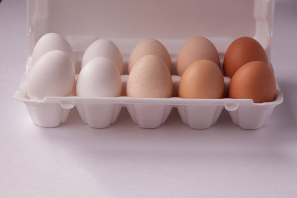 卵の箱の中に色の違う有機鶏の卵。鶏の異なる品種の卵. - 写真・画像