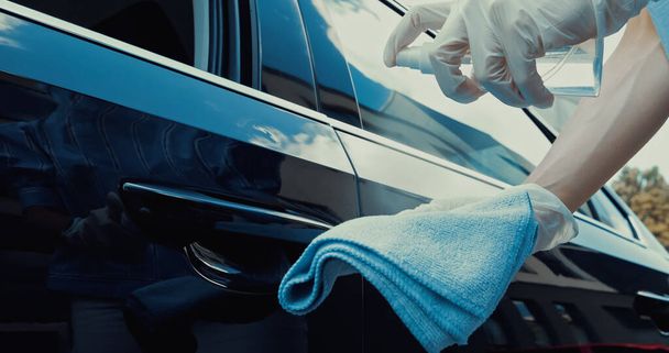 bijgesneden zicht van de vrouw in latex handschoenen spuiten desinfecterend middel op doek - Foto, afbeelding